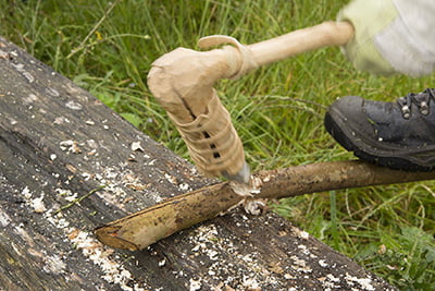 Hout wordt bewerkt met een nagemaakte prehistorische dissel met leren omwikkeling